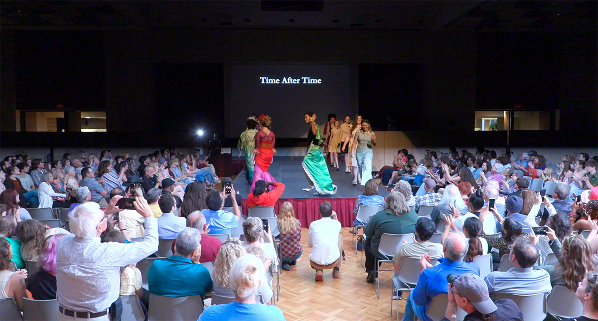 Fashion show attendees watch the runway models.