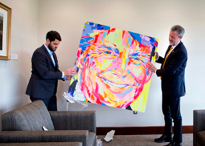 two people hanging up abstract painting of a face