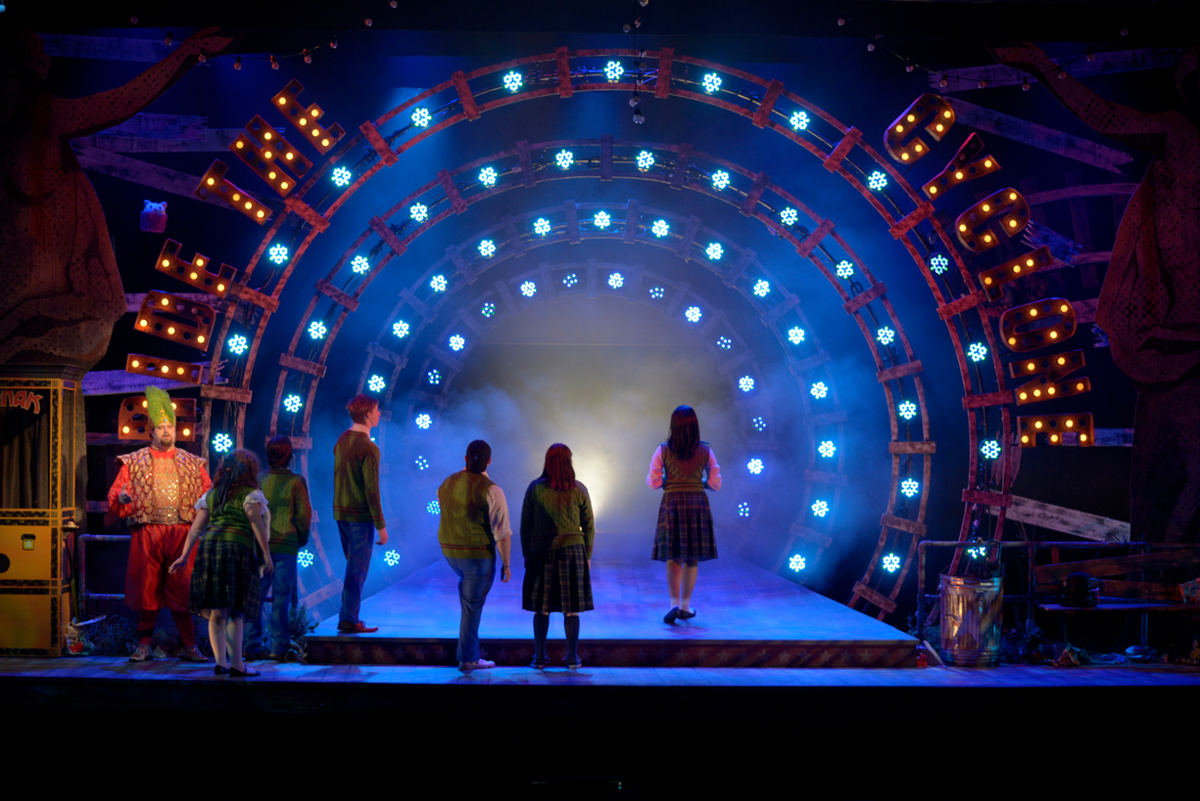 wide shot of dark stage with actors backs to audience